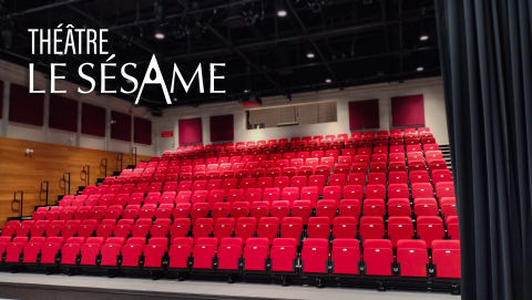 Salle vide du Théâtre Le Sésame avec des sièges rouges en gradins, vue depuis la scène avec le logo en haut à gauche