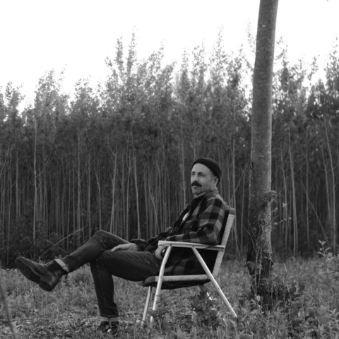 Une image de l'artiste installé sur une chaise dans les bois.
