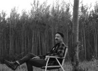 Une image de l'artiste installé sur une chaise dans les bois.
