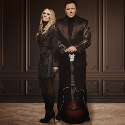 Les artistes Maxime Landry et Annie Blanchard debout tenant une guitare à la main.